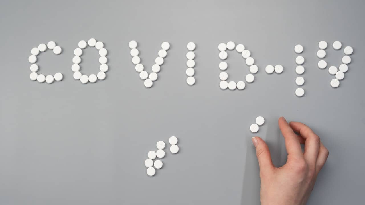 a hand making a pattern from white tablets saying covid 19