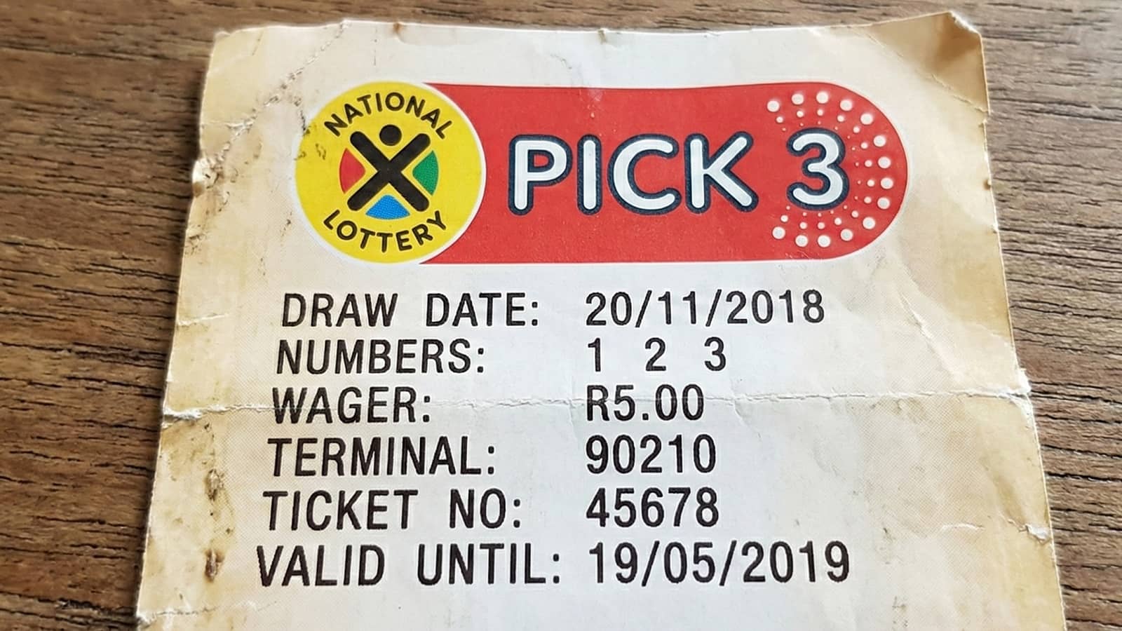 close-up of a printed South African National Lottery Pick 3 ticket resting on a wooden surface