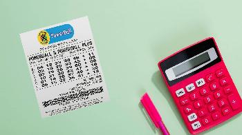 south africa powerball ticket and pen and calculator on green surface